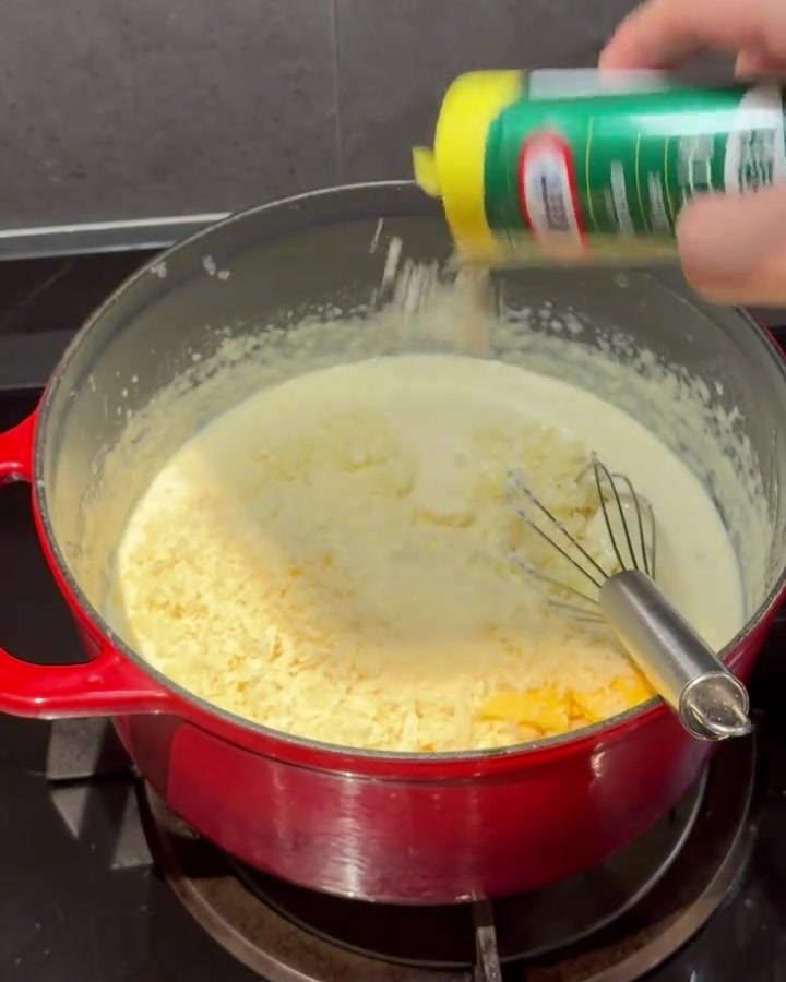 Poudre de fromage incorporée à la sauce crémeuse dans la casserole.