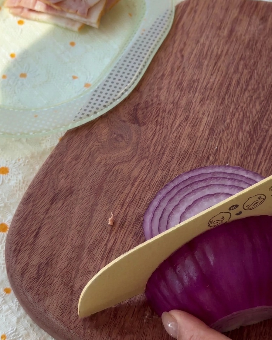 Oignon rouge cru émincé finement sur une planche en bois.