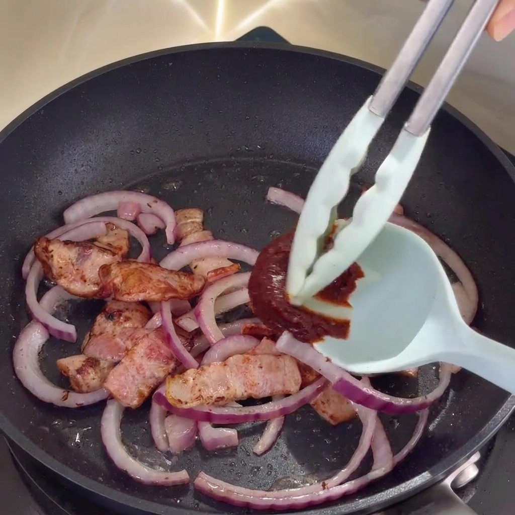 Sauce coréenne mélangée au bacon et aux oignons dans la poêle.