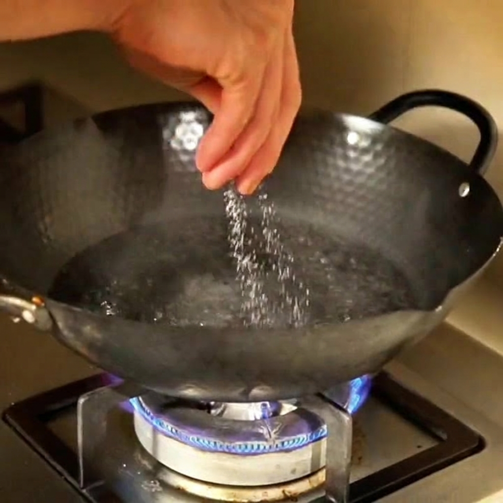 Une main jetant du sel dans une grande casserole deau bouillante sur la cuisinière.