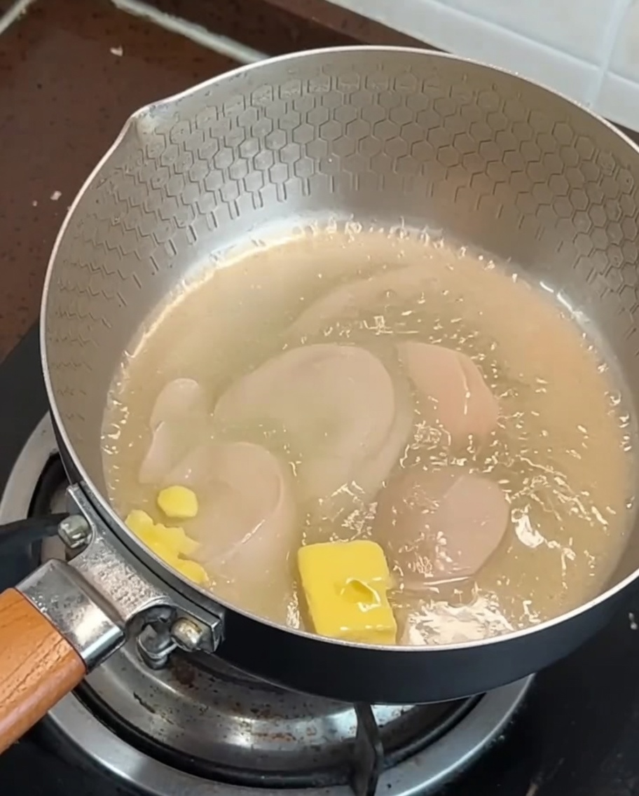 Tranches de bacon et ail qui rissolent dans une poêle avec du beurre fondu.
