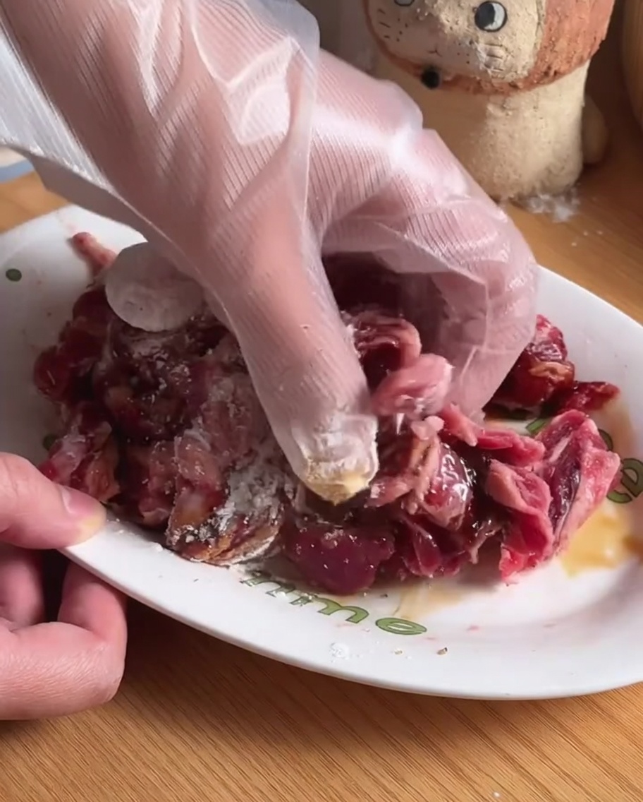 Lanières de bœuf mélangées avec des assaisonnements et la marinade dans un bol blanc.