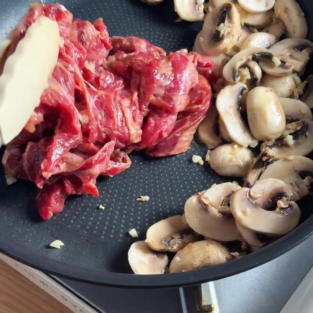 Lanières de bœuf marinées sautant dans une poêle avec des champignons émincés.