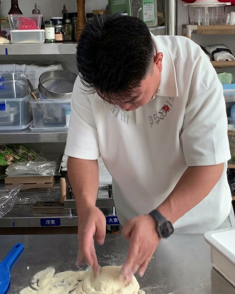 Des mains pressant une boule de pâte pour commencer à former une base de pizza plate et ronde.