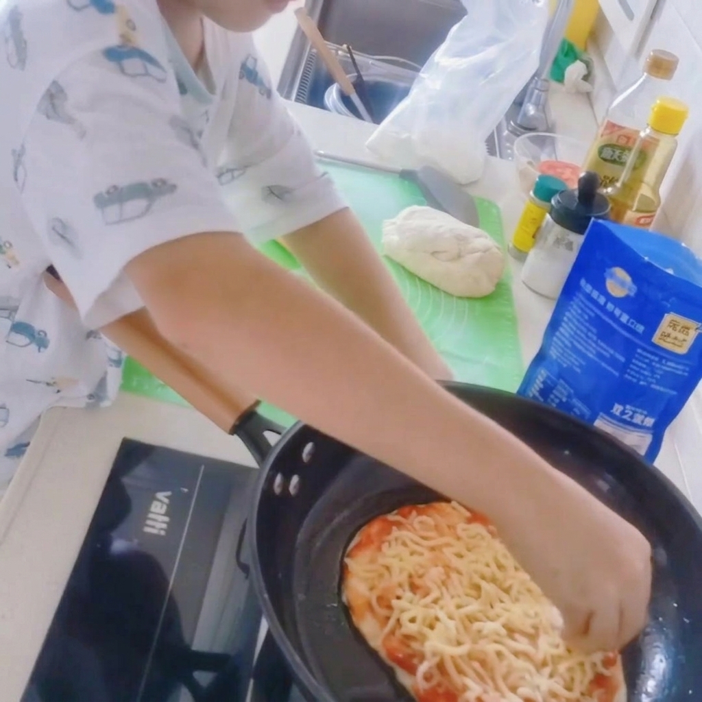Gros plan dune base de pizza dans une poêle, garnie dune épaisse couche de mozzarella râpée.