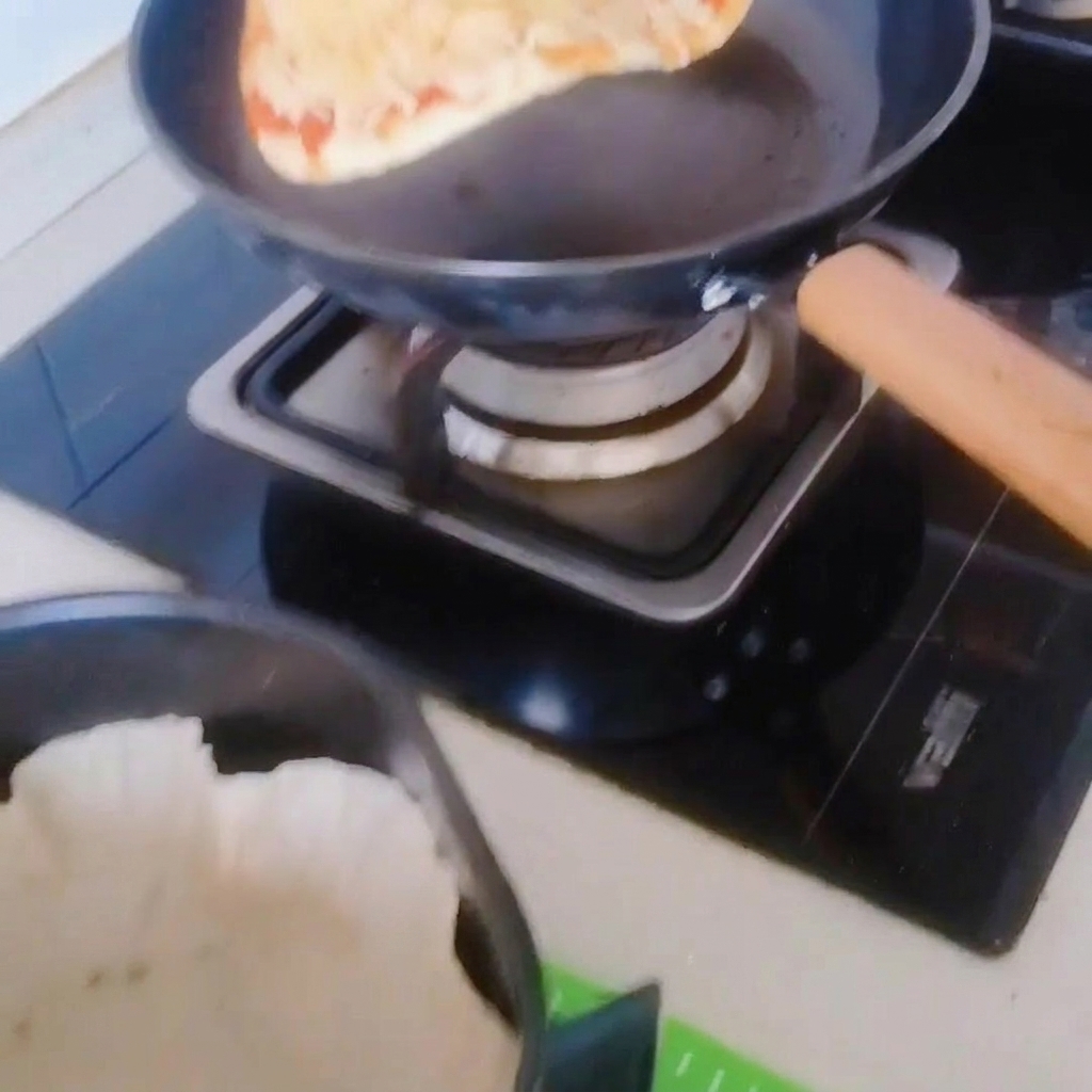 La pizza délicatement transférée de la poêle vers le panier de lair fryer doublé de papier cuisson.