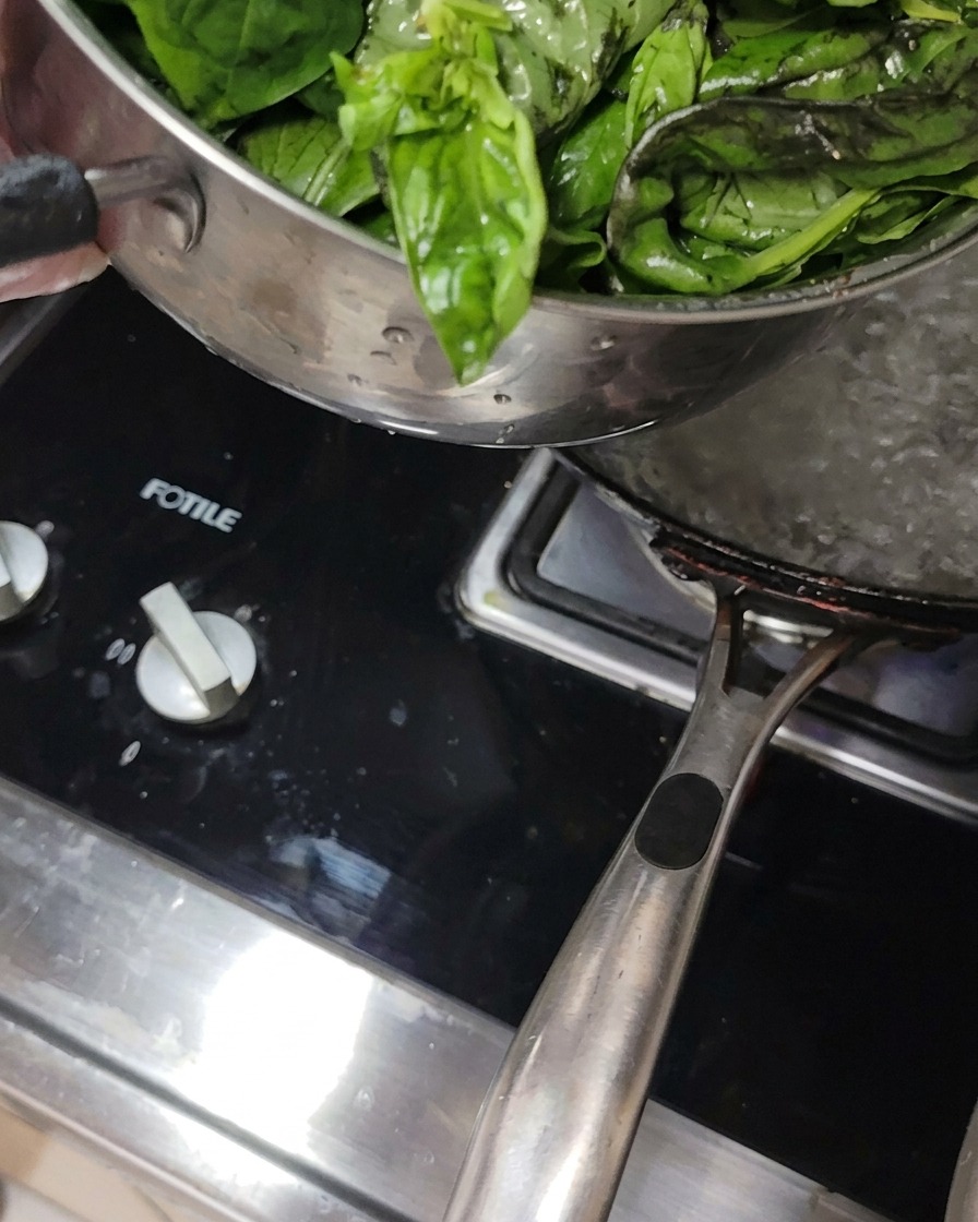 Feuilles de basilic frais plongées dans une casserole deau bouillante sur une cuisinière.