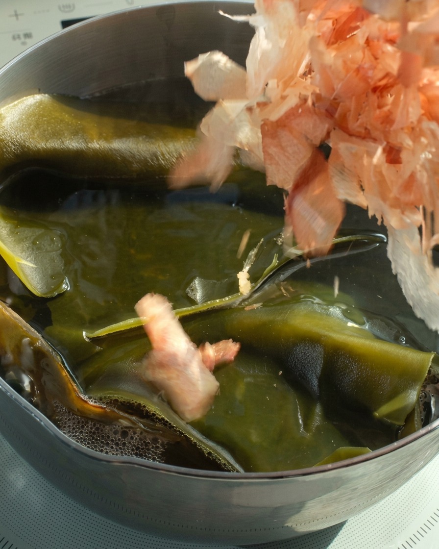 Des flocons de bonite ajoutés dans une casserole de bouillon de kombu chaud.