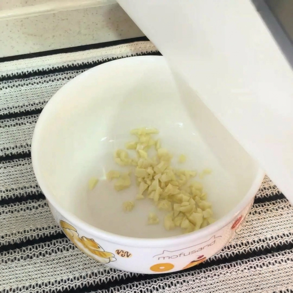 Gros plan sur un bol blanc contenant de lail haché, un jaune dœuf cru, lassaisonnement des nouilles et de la mayonnaise, prêt à être mélangé.