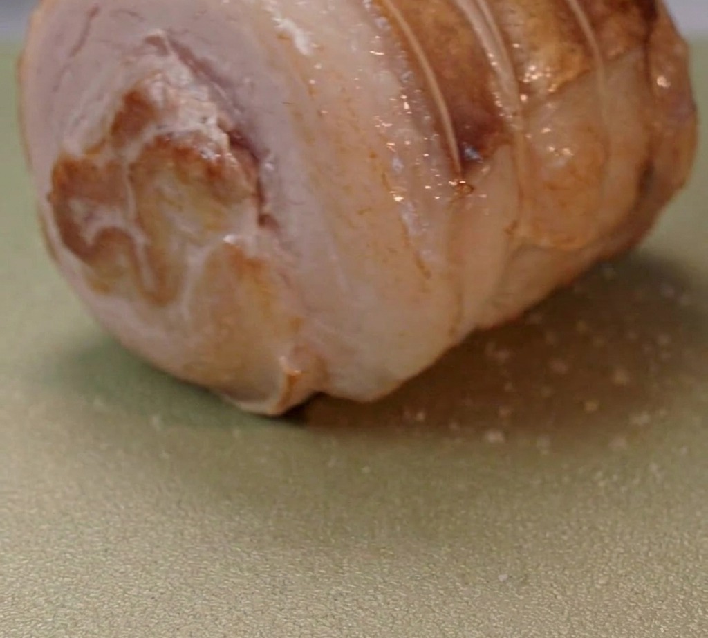 Poitrine de porc roulée en train de dorer dans une poêle avec de lhuile chaude.