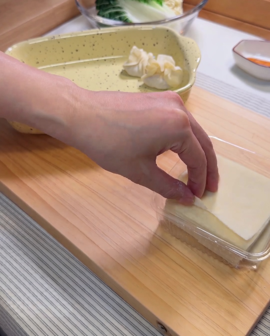 Une feuille de wonton crue dans la paume dune main avec une noix de farce aux crevettes au centre.