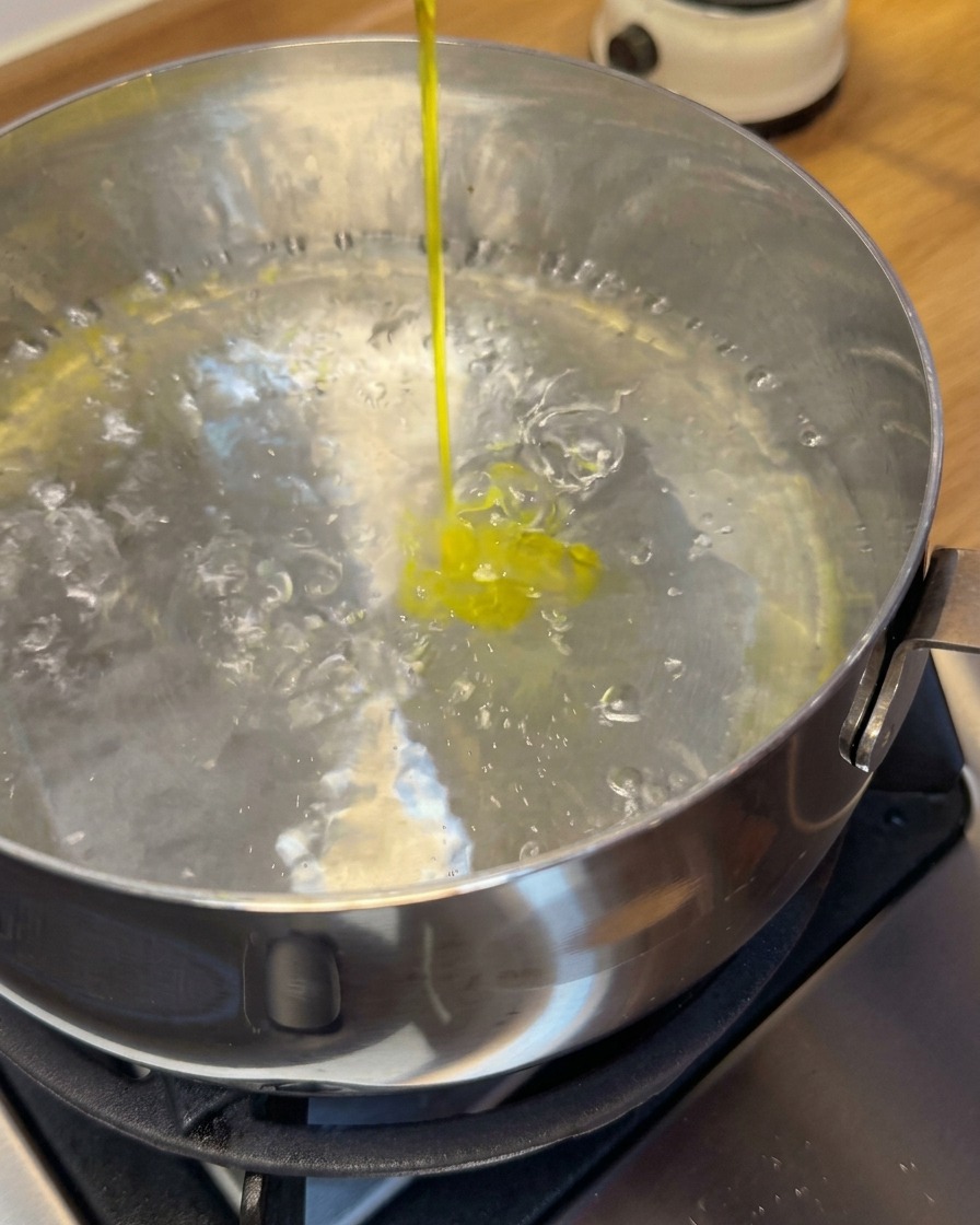 Wontons de crevettes crus plongés dans une casserole deau bouillante avec une écumoire.