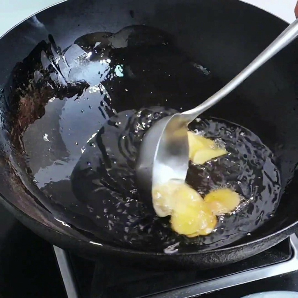 Tranches de gingembre et têtes de crevettes saisies dans un wok avec de lhuile chaude.