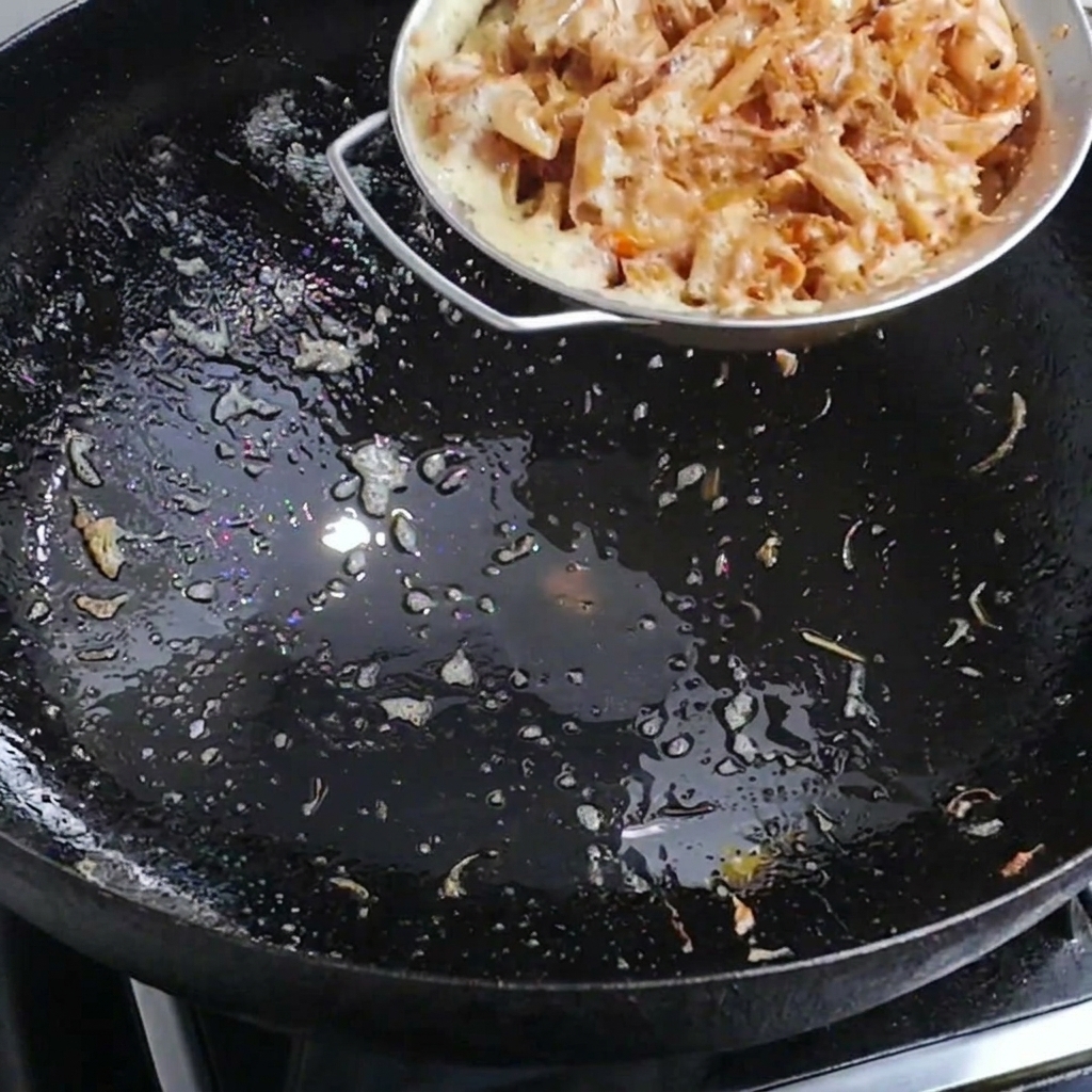 Eau bouillante versée sur des carapaces de crevettes dans un wok pour créer un bouillon parfumé.