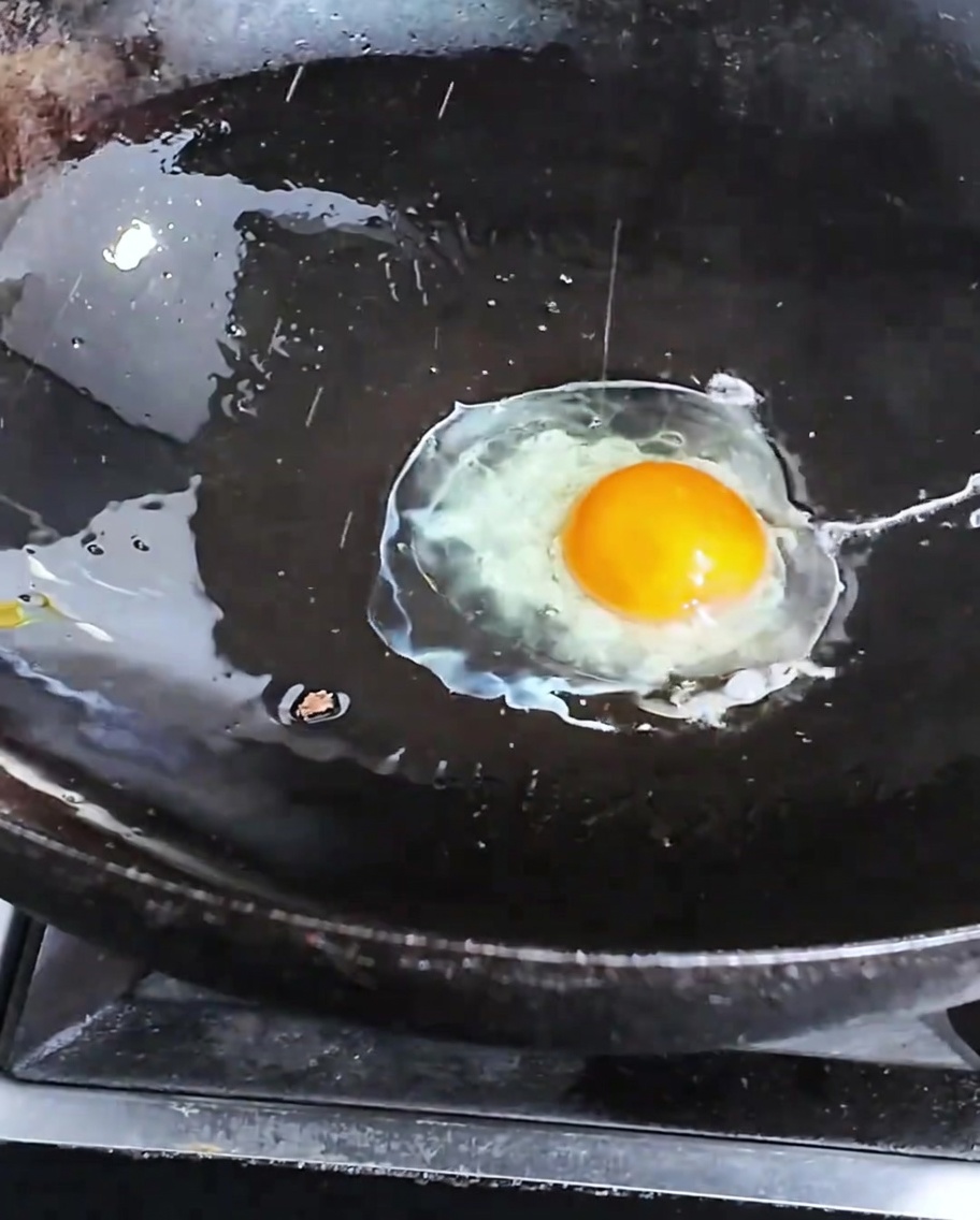 Un œuf en train de frire dans un wok chaud.