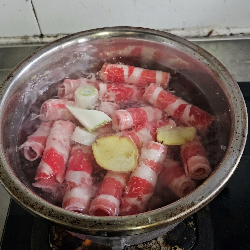 Tranches de bœuf bouillies dans une casserole avec des aromates et du vin de cuisine.