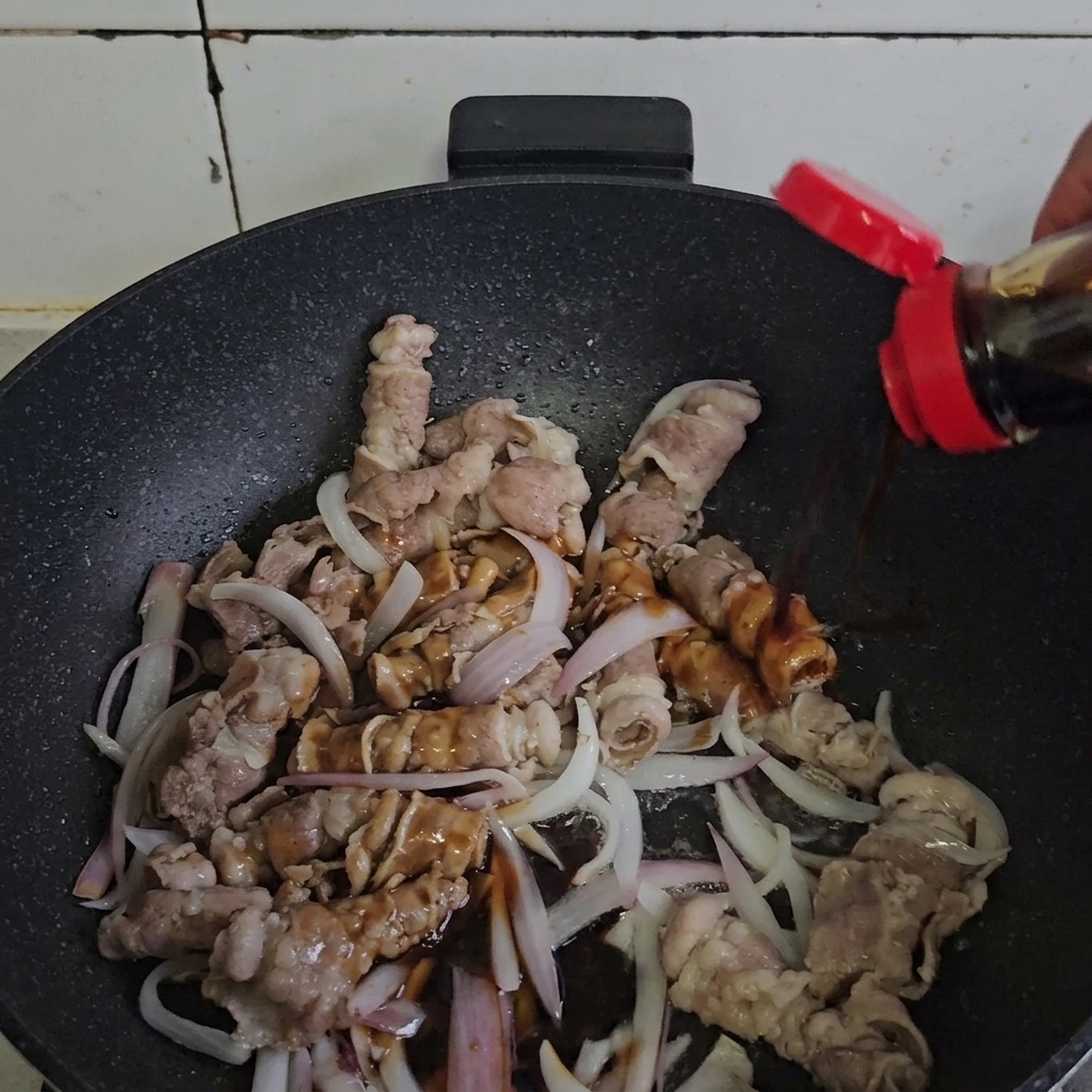Bœuf et oignons mélangés avec la sauce dans une poêle chaude.