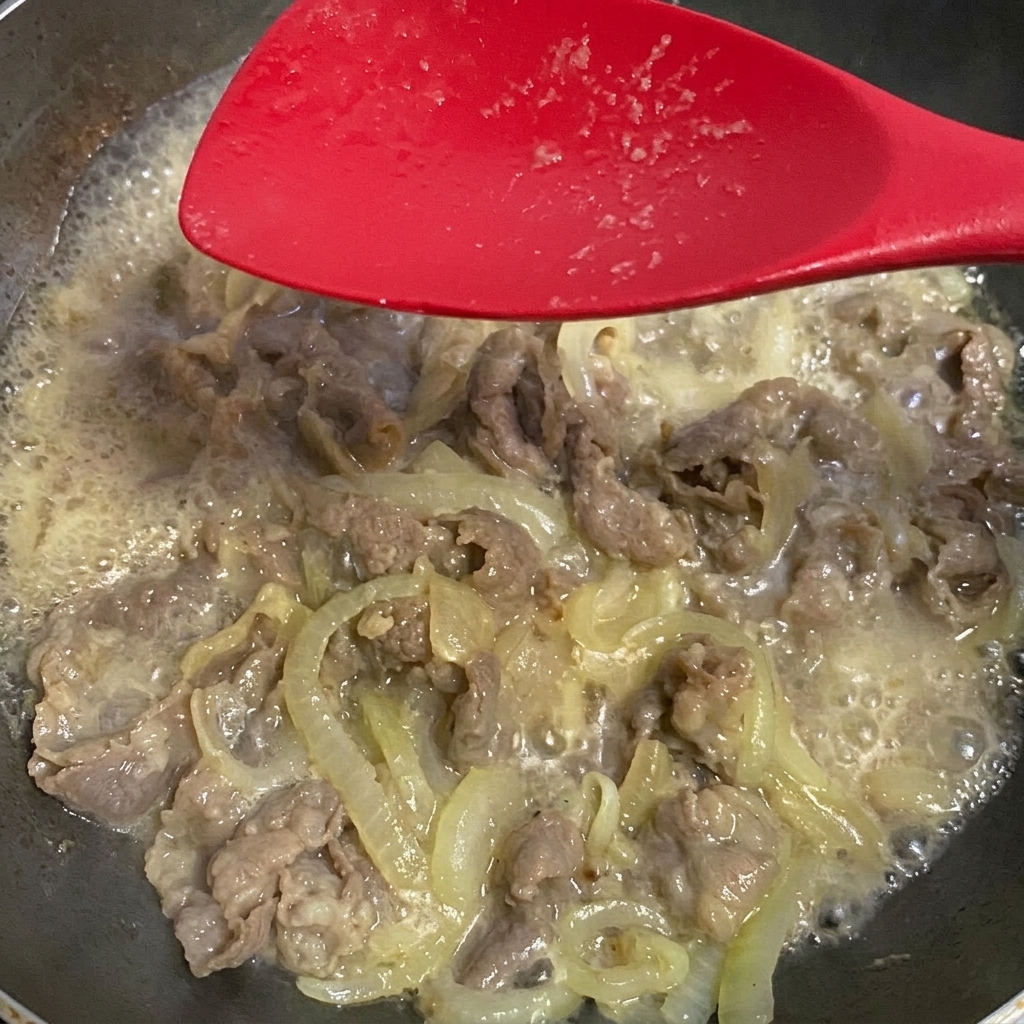 Sauce soja ajoutée au mélange de bœuf et doignons frémissant.