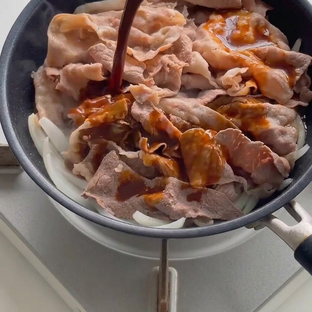 Sauce sombre savoureuse versée sur le bœuf et les oignons dans une poêle chaude.
