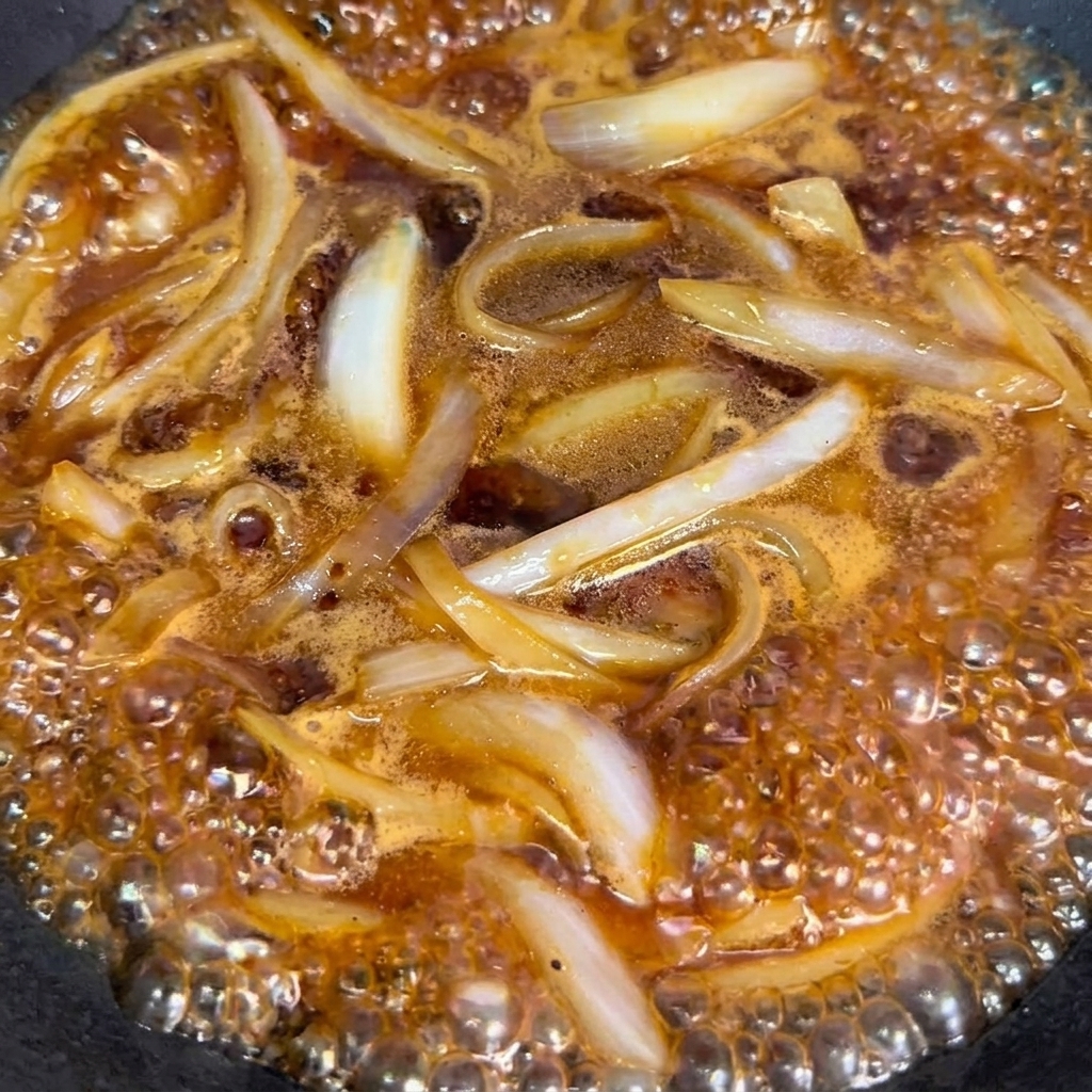 Bœuf blanchi ajouté au wok avec les oignons et la sauce.