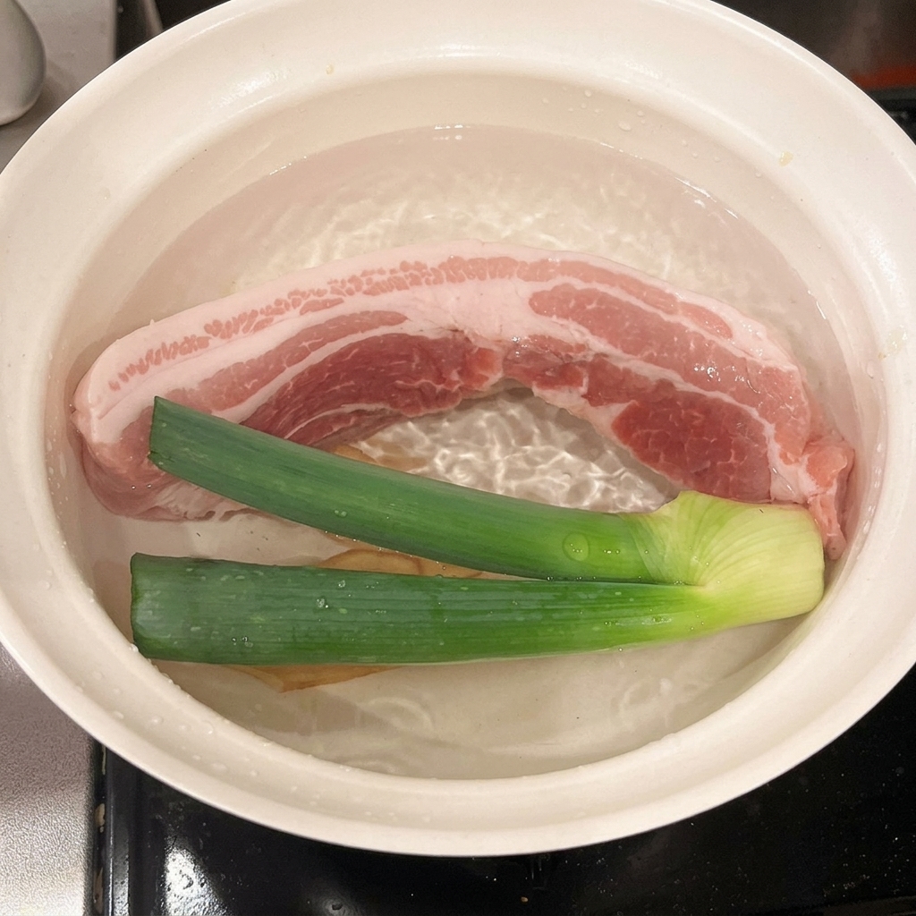 Vin de cuisson versé dans une casserole contenant la poitrine de porc, loignon vert et le gingembre.