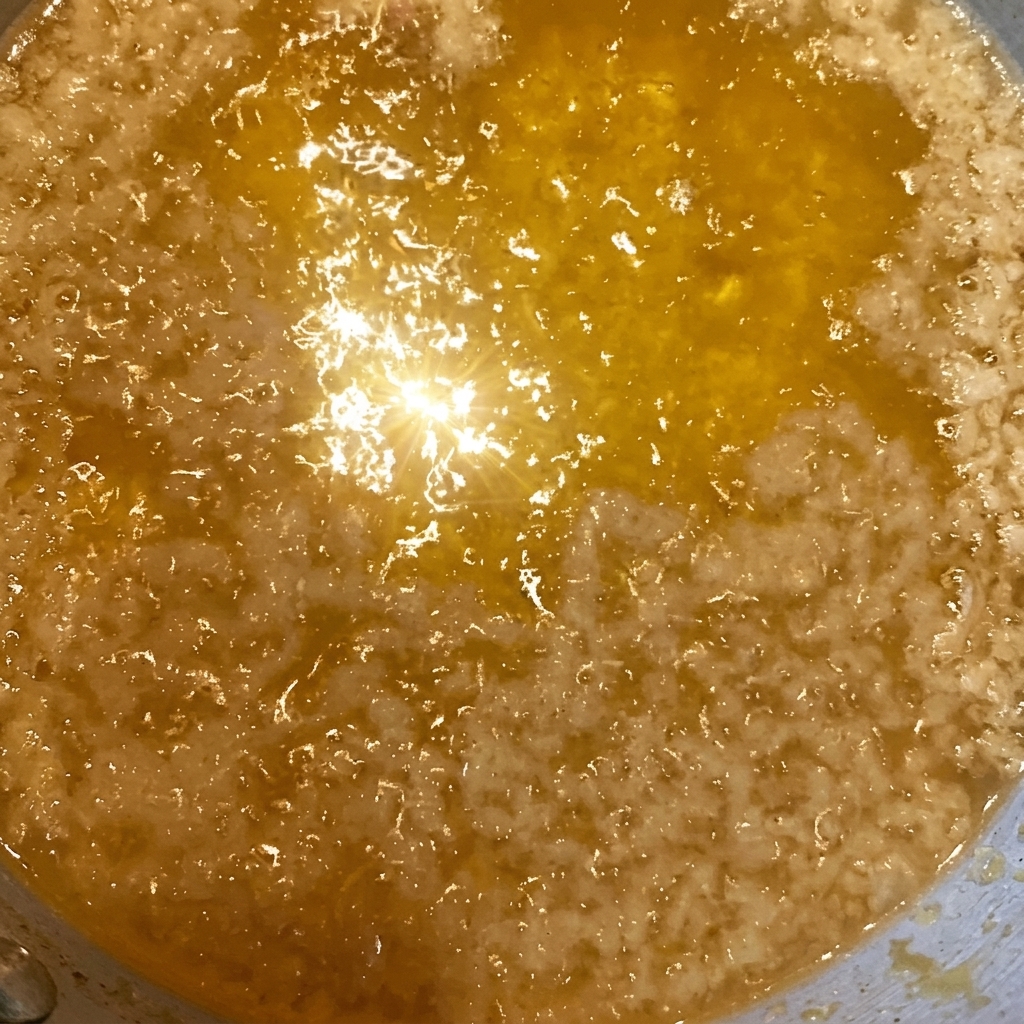 Gros plan sur des miettes de tempura dorées parsemées sur un bol de riz nappé de sauce soja.