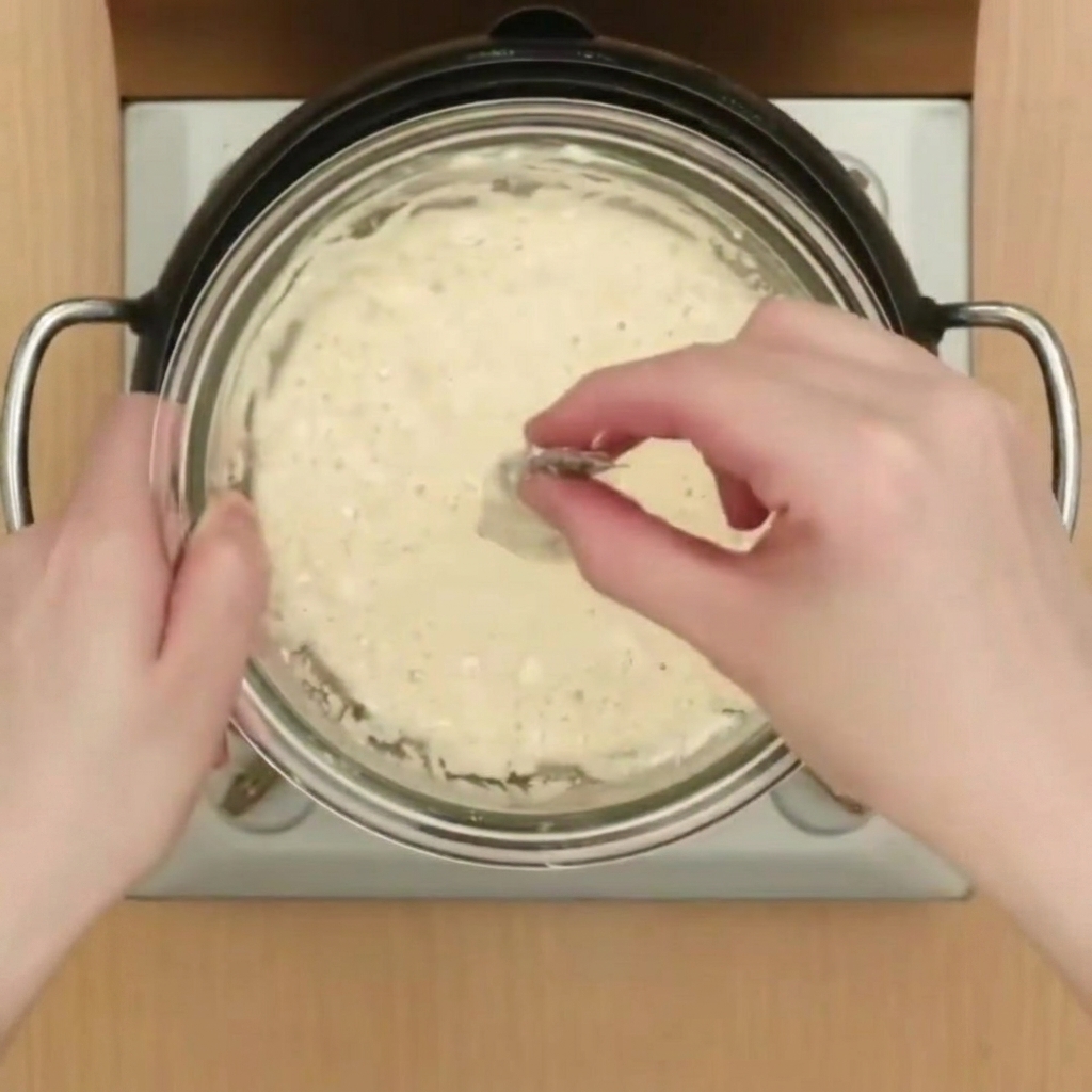 Une crevette enrobée dune fine pâte à tempura avant dêtre plongée dans une casserole dhuile chaude et bouillonnante.