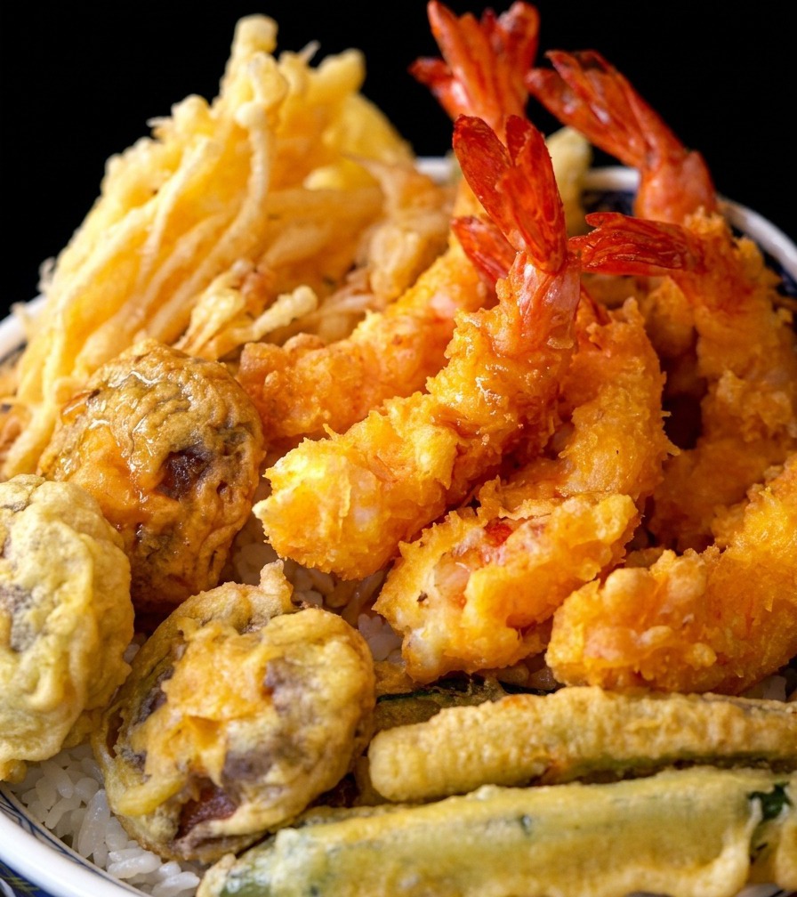 Un bol de riz tempura terminé, garni de crevettes et de légumes frits croustillants.