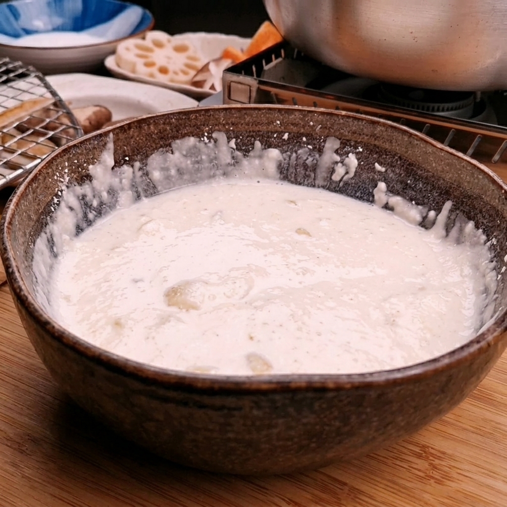 Eau glacée versée dans un bol de farine à tempura pour créer une pâte lisse.