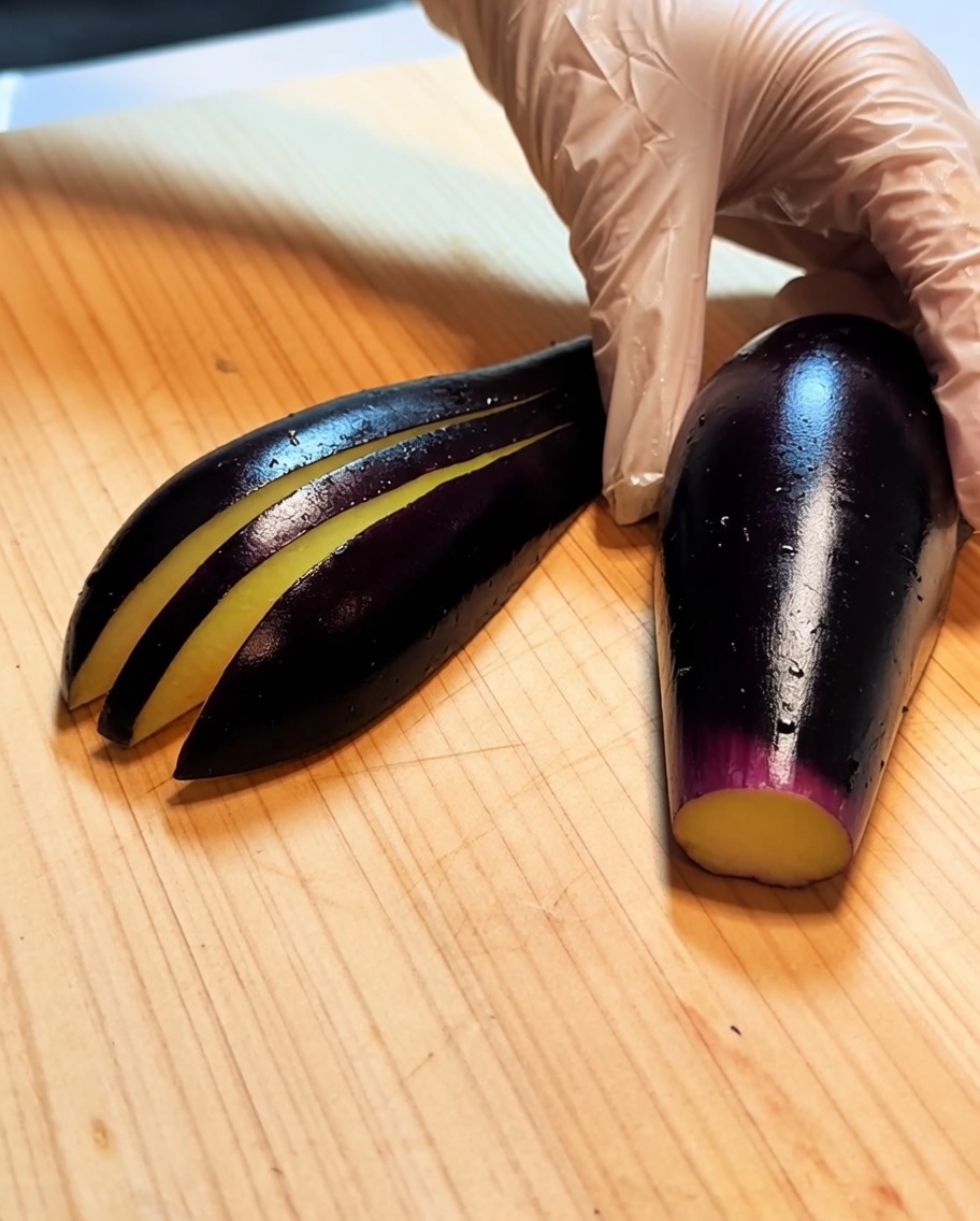 Une aubergine sur une planche en bois avec plusieurs incisions parallèles légères sur sa longueur.