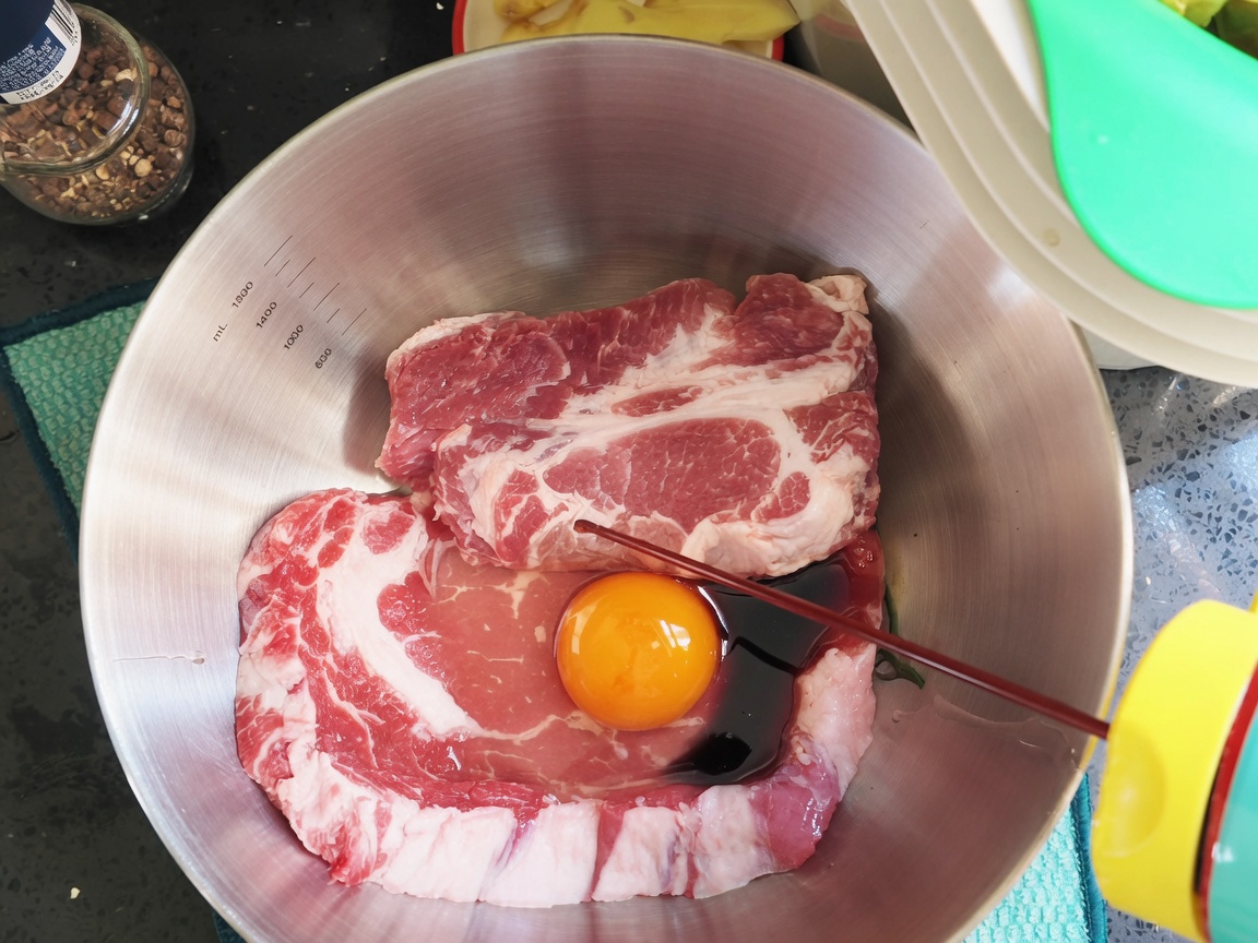 Sauce soja et assaisonnements versés sur les côtes de porc et lœuf dans le bol.