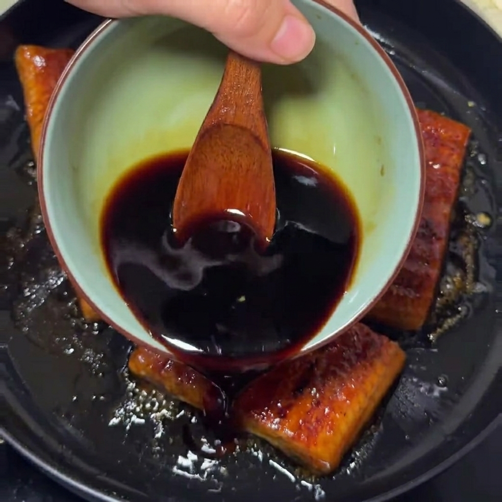 La sauce savoureuse versée sur les filets danguille dans la poêle.