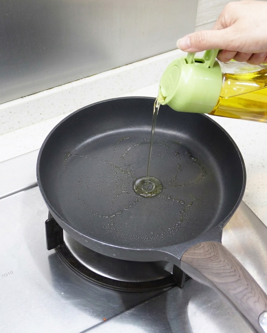 Vue rapprochée dhuile versée dans une poêle antiadhésive préchauffée, prête pour languille.
