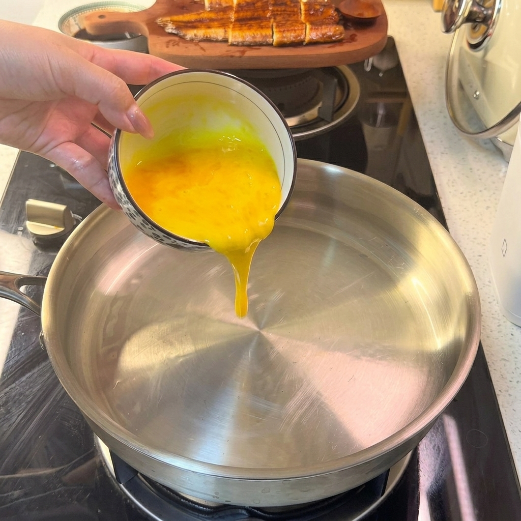 Le mélange dœuf liquide versé dans une poêle chaude, commençant à former une fine couche.