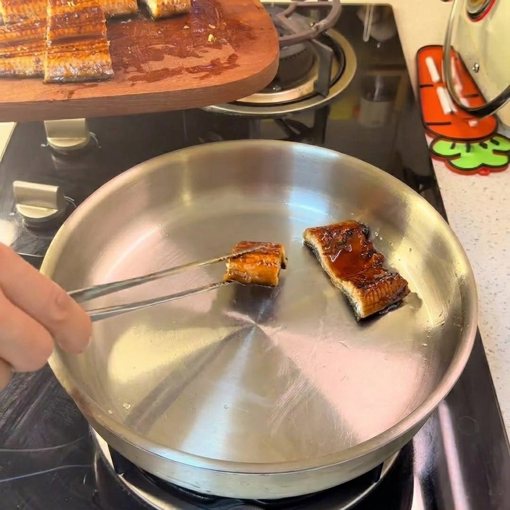 Morceaux danguille dans une poêle en inox, sautés délicatement à feu doux.