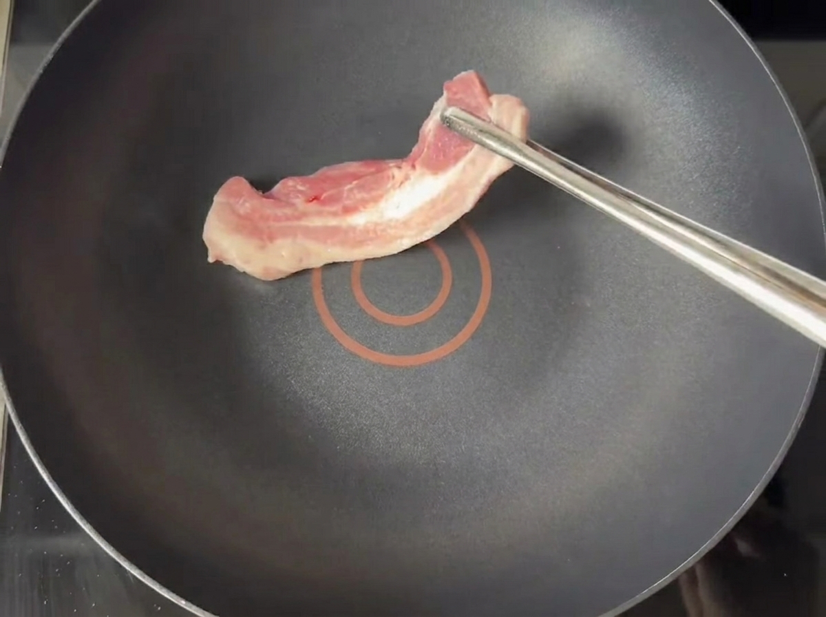 Tranches de poitrine de porc dorant dans une poêle sèche.