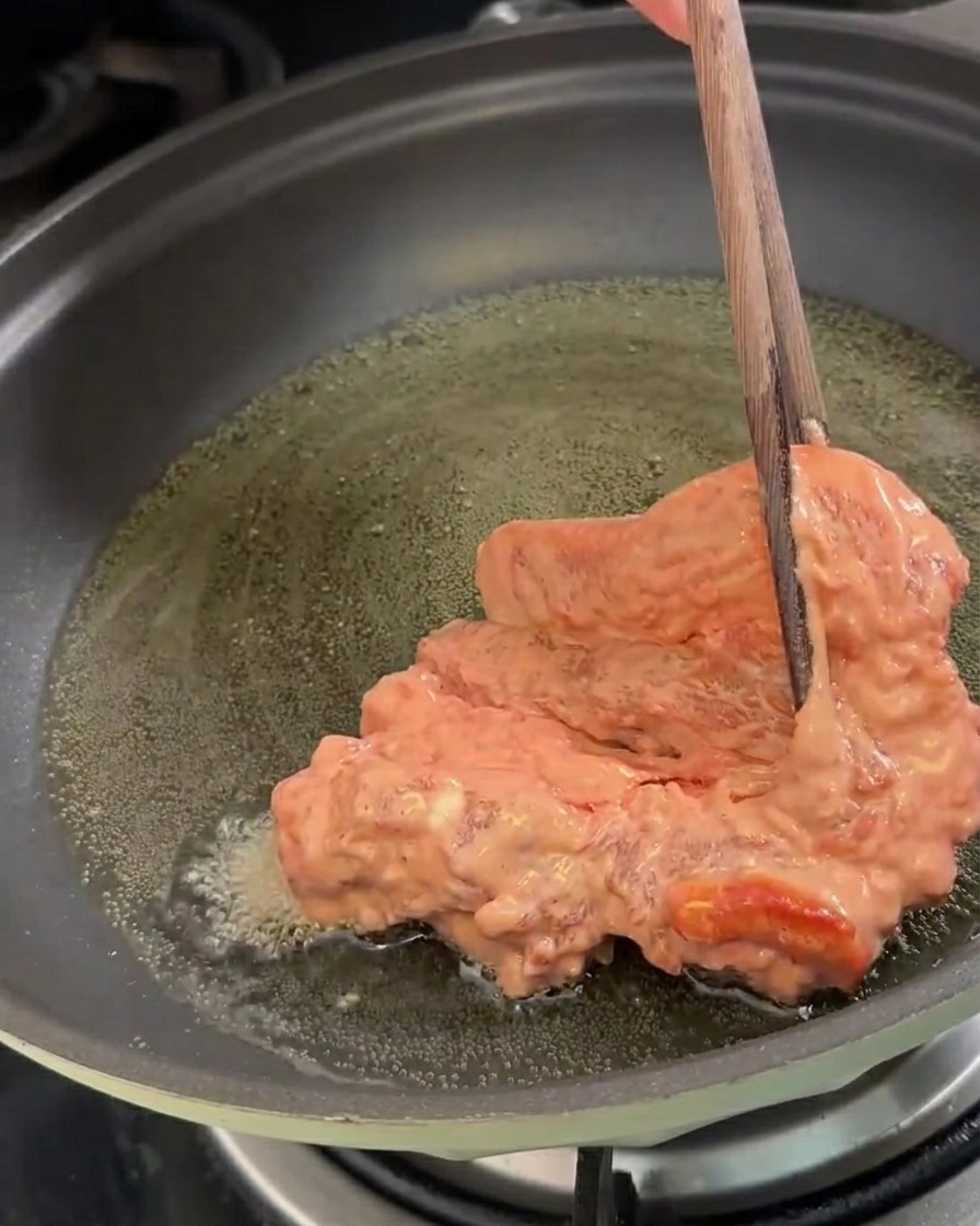 Morceaux de porc marinés déposés dans une poêle dhuile chaude pour la friture.