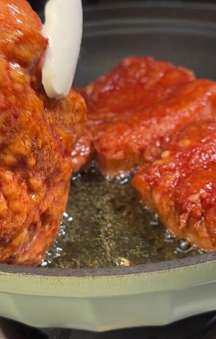 Lanières de poitrine de porc en train de frire dans une poêle, prenant une couleur dorée.