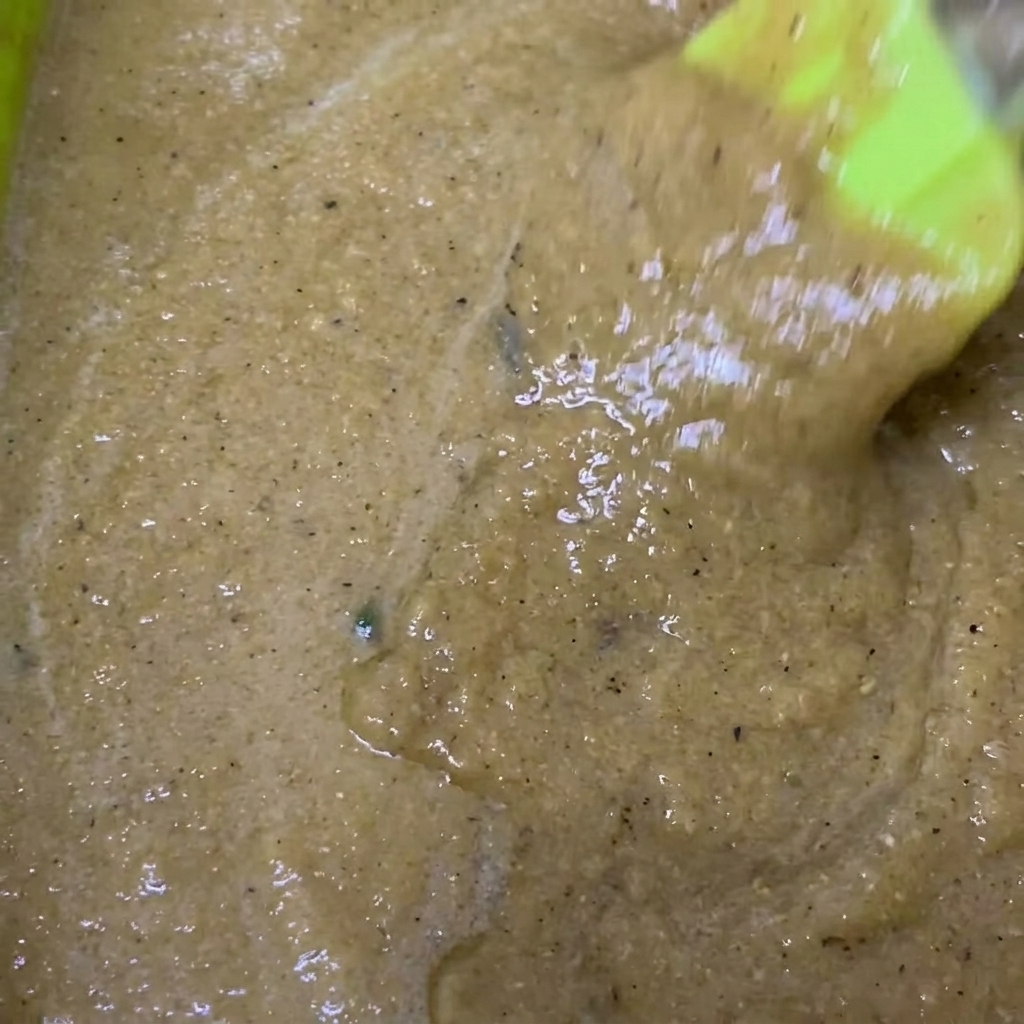 Bol mélangeur contenant la marinade mixée avec la sauce soja et le poivre noir ajoutés.