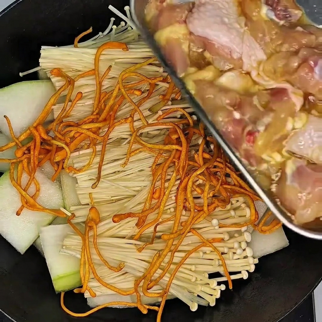 Une main gantée massant les pilons de poulet dans un bol de marinade.