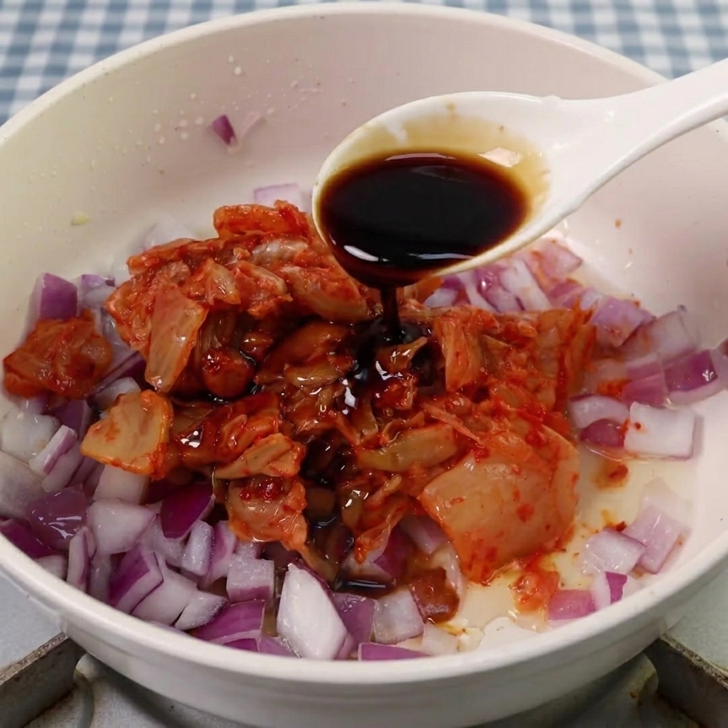 Sauce soja, sucre et pâte épicée coréenne ajoutés au mélange de kimchi et doignons.