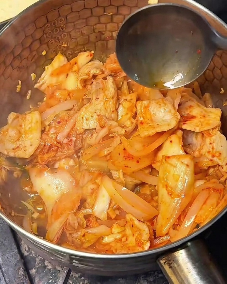 Sauce soja légère versée sur le mélange de kimchi et porc.