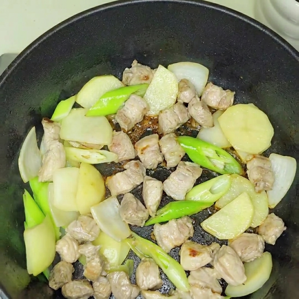 Du kimchi fraîchement ajouté dans la base de porc et doignons en train de revenir.