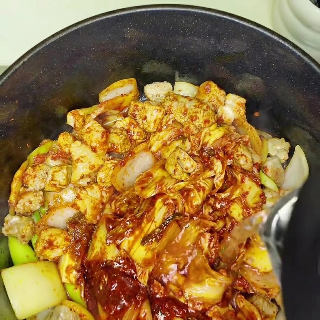 De leau ajoutée à la marmite contenant le kimchi et le porc, marquant le début du mijotage.