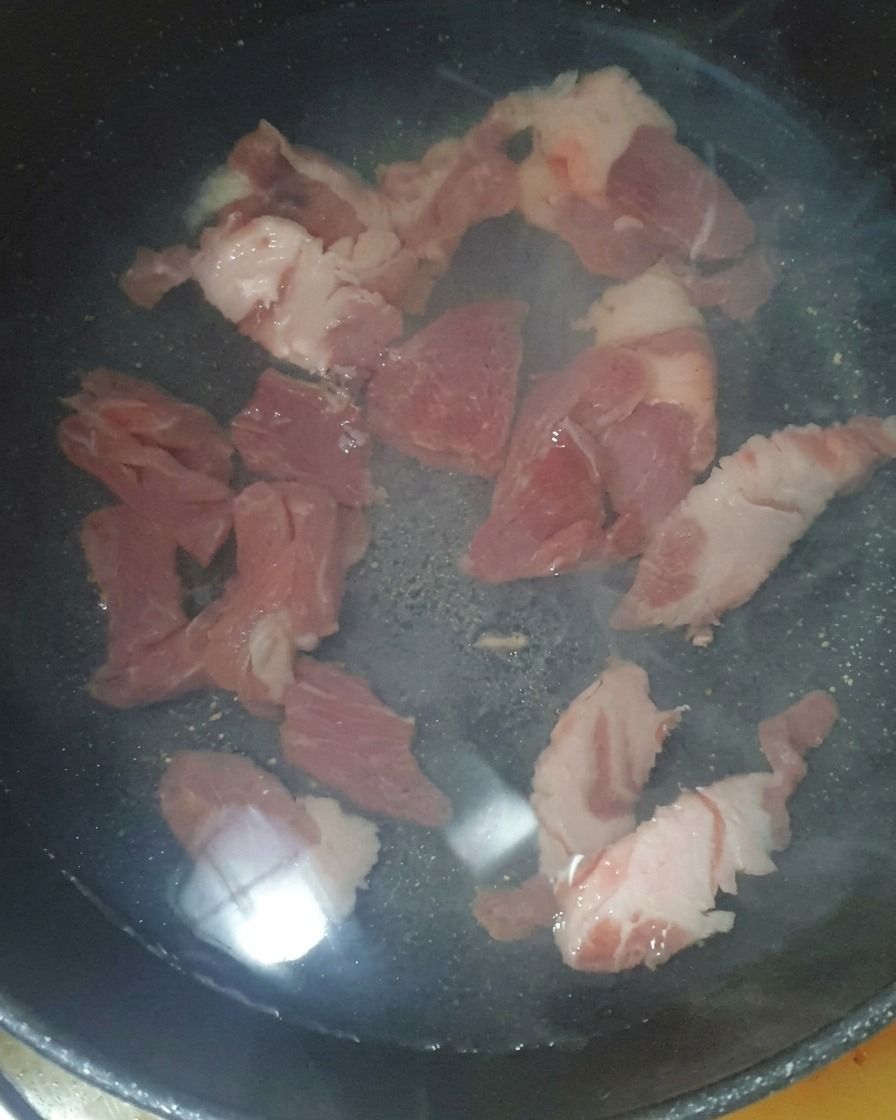 Morceaux de porc immergés dans leau avec une cuillerée de crevettes salées.