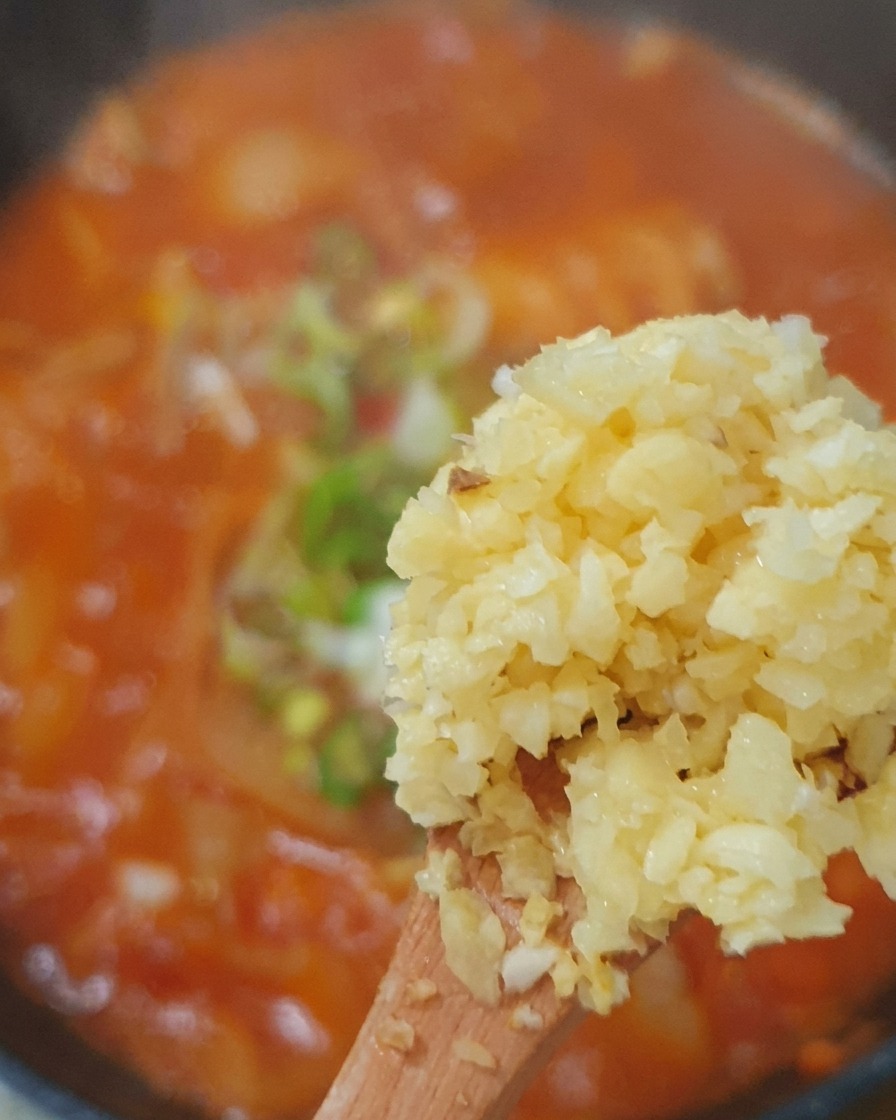 Ail haché, oignons verts et piments ajoutés au bouillon.