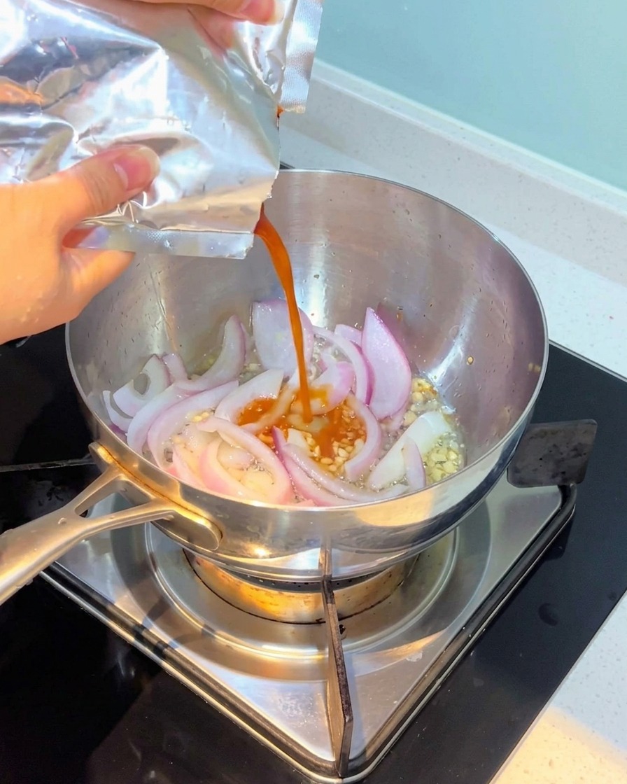 Kimchi versé dans la casserole et mélangé avec les oignons et lail.