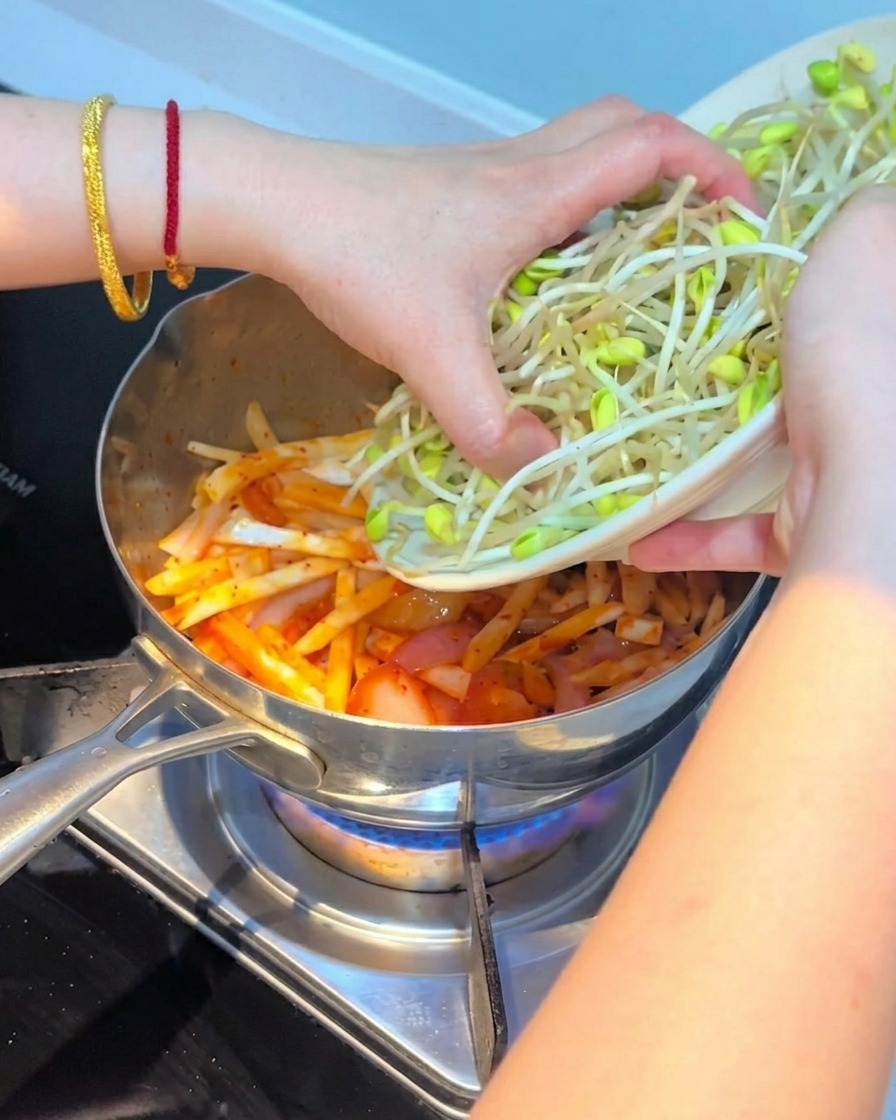 Pousses de soja fraîches disposées sur le mélange de kimchi et de champignons.