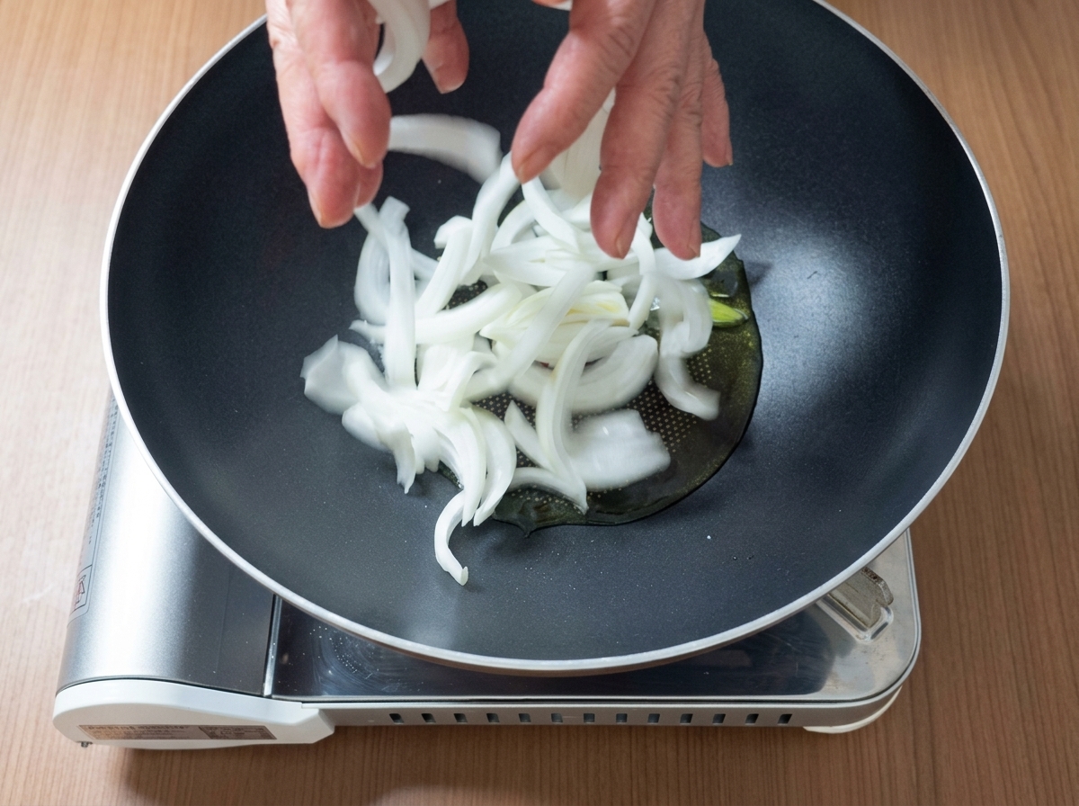 Morceaux de porc et oignons tranchés grésillant ensemble dans une poêle avec de lhuile.