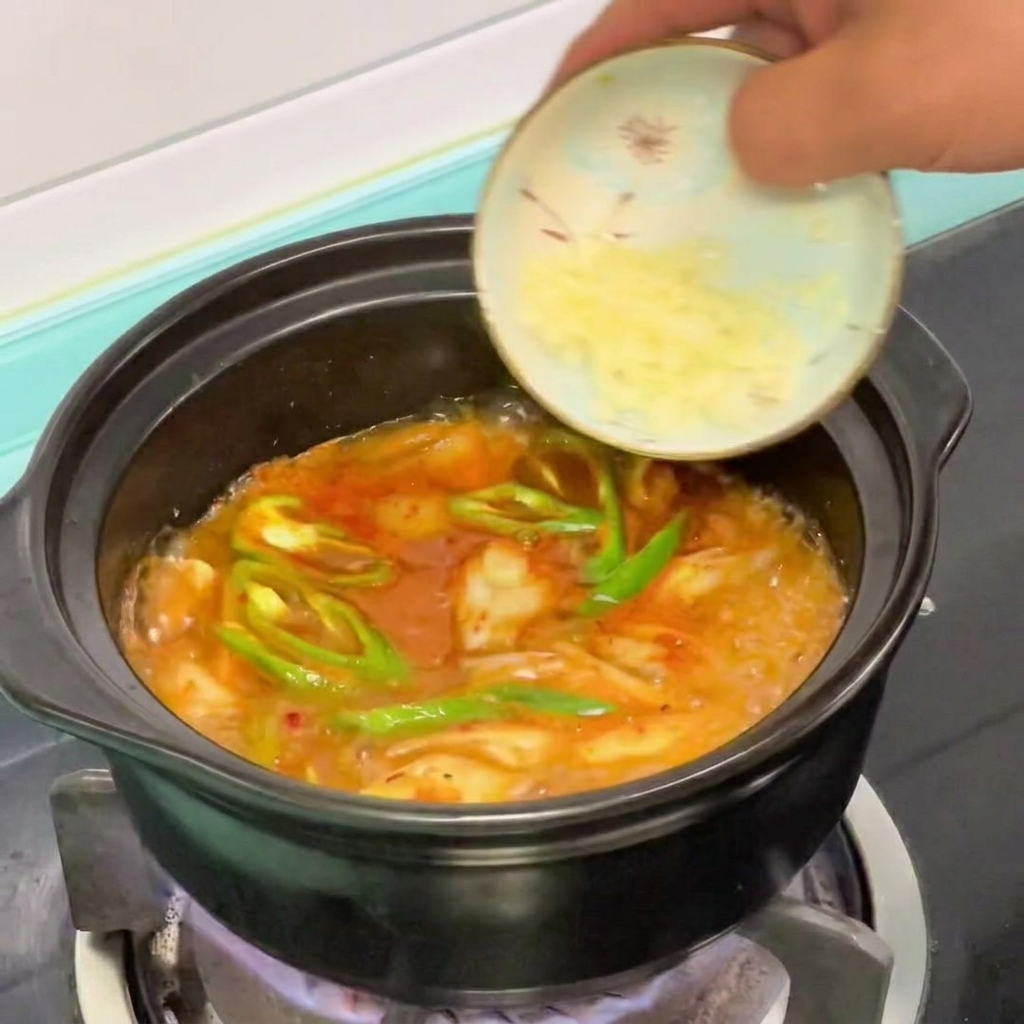 Ail haché ajouté dans une casserole de ragoût de tofu soyeux coréen frémissant.